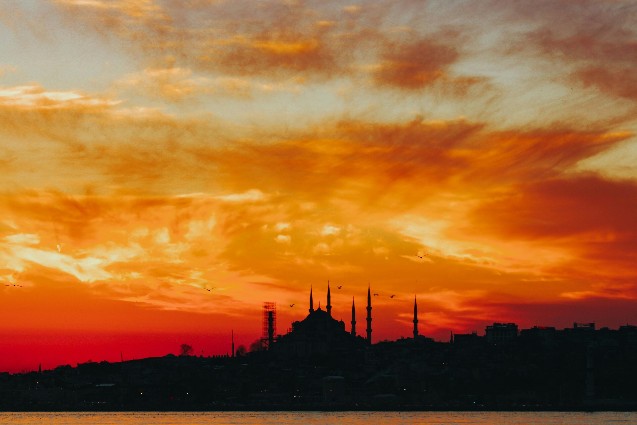 Cheap flights to Istanbul from London, Dramatic silhouette of a mosque against a vibrant sunset sky in Istanbul, Turkey.